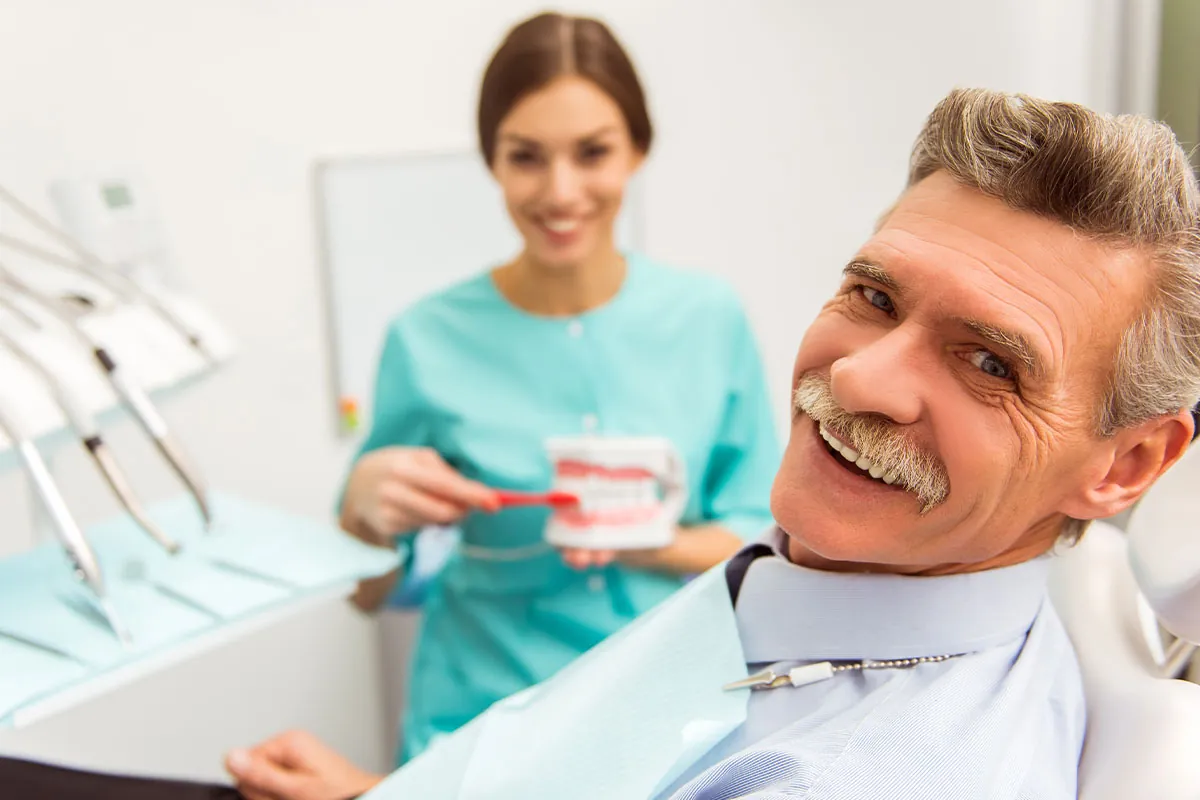 Dentist teaching how to brush the dentures to her patient